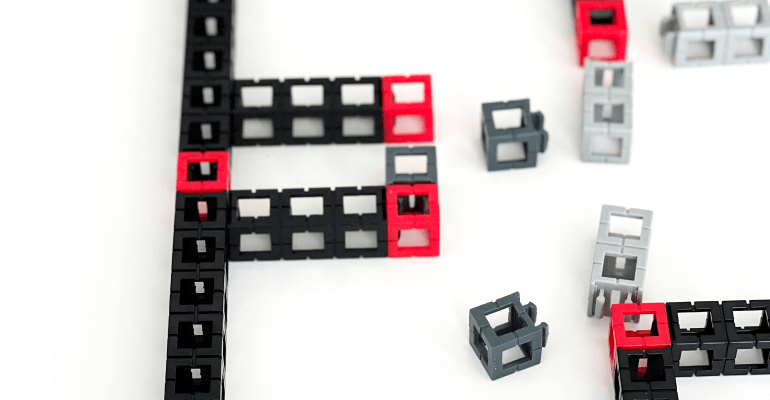 Red, black, and gray STEM learning blocks laid on a white table in the process of being put together