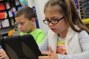 Young students explore STEM using a tablet to complete their lesson