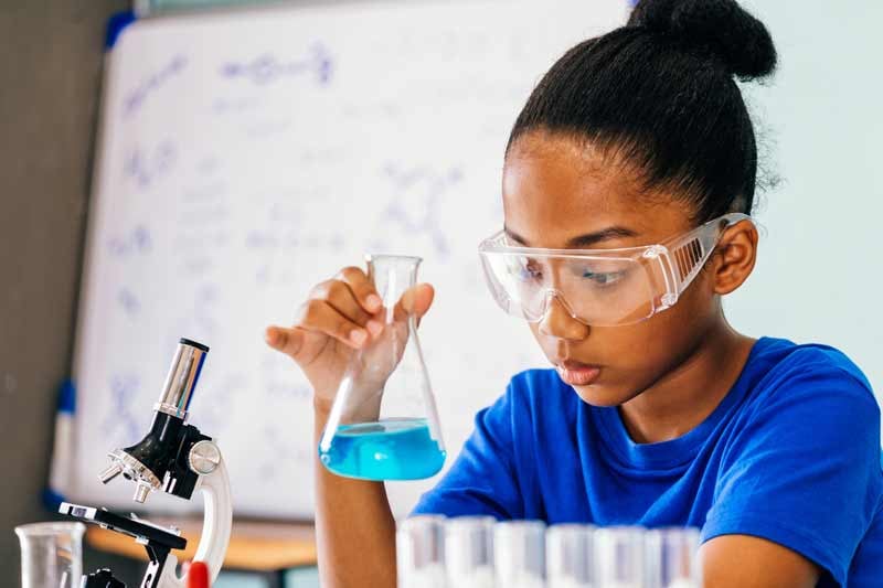 young female student with a beaker working on scientific work